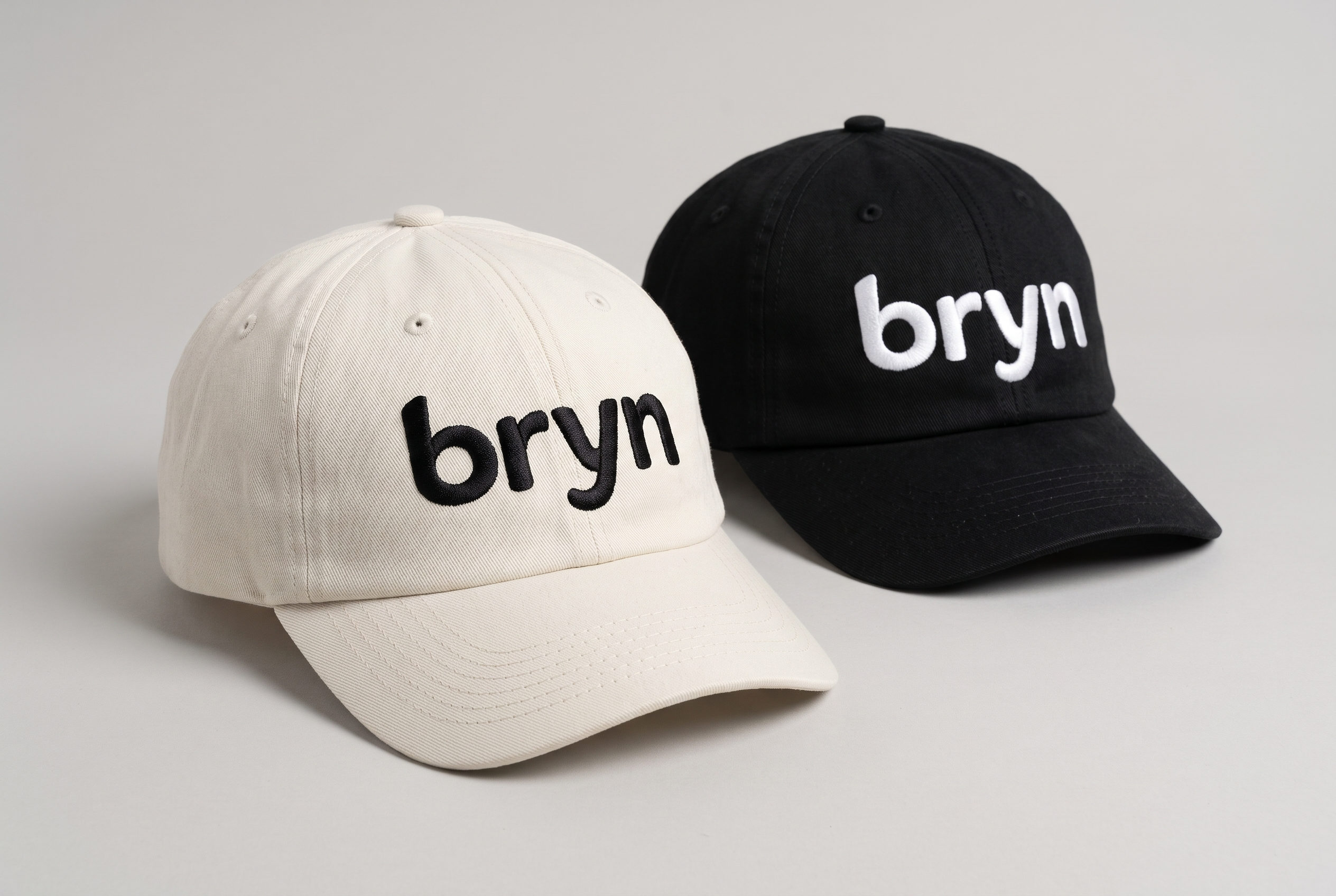 The Natural wordmark embroidered in black on a light cap and white on a dark cap